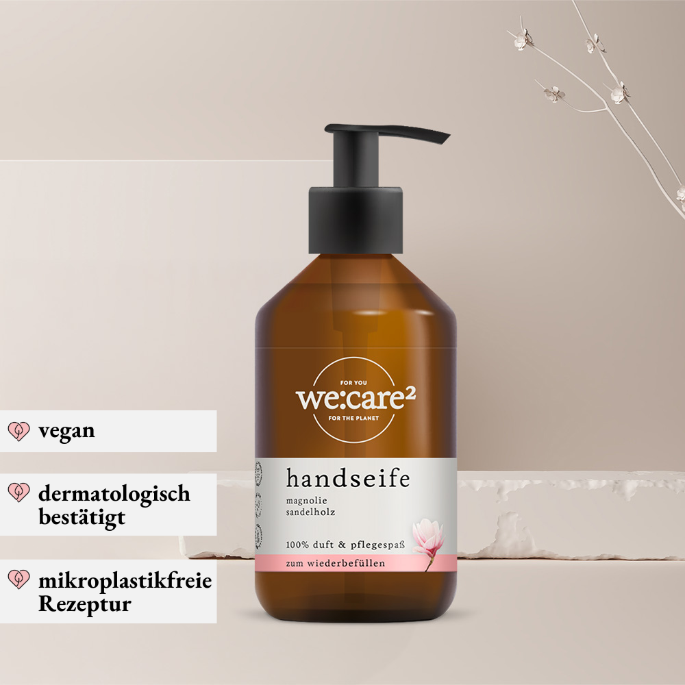 Braune Glas-Pumpflasche „we:care²“ Handseife mit Magnolie- und Sandelholzduft auf hellem, minimalistischem Hintergrund; links hervorgehoben mit den Eigenschaften vegan, dermatologisch bestätigt und mikroplastikfreie Rezeptur.