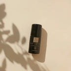 Schwarzer „THATS me ORGANIC“ Deo Roll-on in einer ästhetischen Nahaufnahme auf hellem Grund mit sanften Schatten von Blättern.