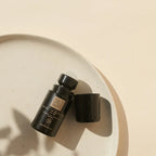 Geöffneter schwarzer „THATS me ORGANIC“ Deo Roll-on mit sichtbarer Kugel und danebenliegender Kappe auf einem hellen, gesprenkelten Keramikteller bei hellem Sonnenlicht.
