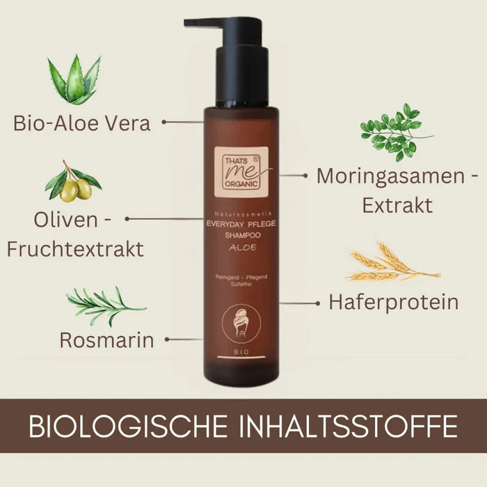 Ästhetische Produktpräsentation bei idery: Eine braune Flasche des flüssigen 'Everyday Pflege Shampoo Aloe' steht auf dem hellen Waschbeckenrand im Badezimmer. Neben der Flasche liegt ein Stück helle Naturseife auf einer Holzschale sowie ein beiges Handtuch. Im Hintergrund sorgen ein runder Wandspiegel mit Holzrahmen und grüne Zimmerpflanzen für eine frische Wohlfühlatmosphäre.