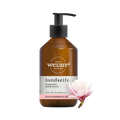 Braune Pumpspenderflasche der Marke "we:care²" für Handseife "Magnolie Sandelholz", mit Etikett-Hinweis "ZUM WIEDERBEFÜLLEN". Rechts daneben eine Magnolienblüte.