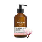 Braune Pumpspenderflasche der Marke "we:care²" für Handseife "Magnolie Sandelholz", mit Etikett-Hinweis "ZUM WIEDERBEFÜLLEN". Rechts daneben eine Magnolienblüte.