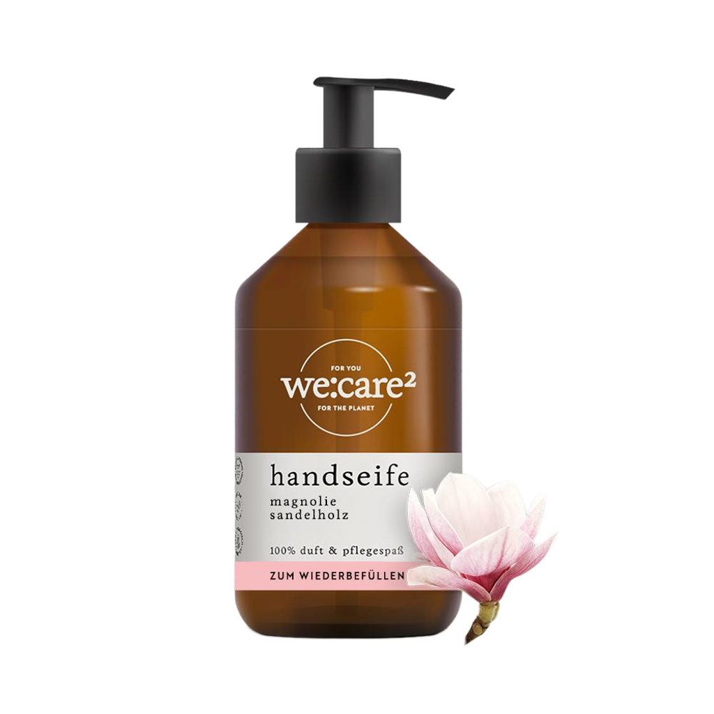 Braune Pumpspenderflasche der Marke "we:care²" für Handseife "Magnolie Sandelholz", mit Etikett-Hinweis "ZUM WIEDERBEFÜLLEN". Rechts daneben eine Magnolienblüte.